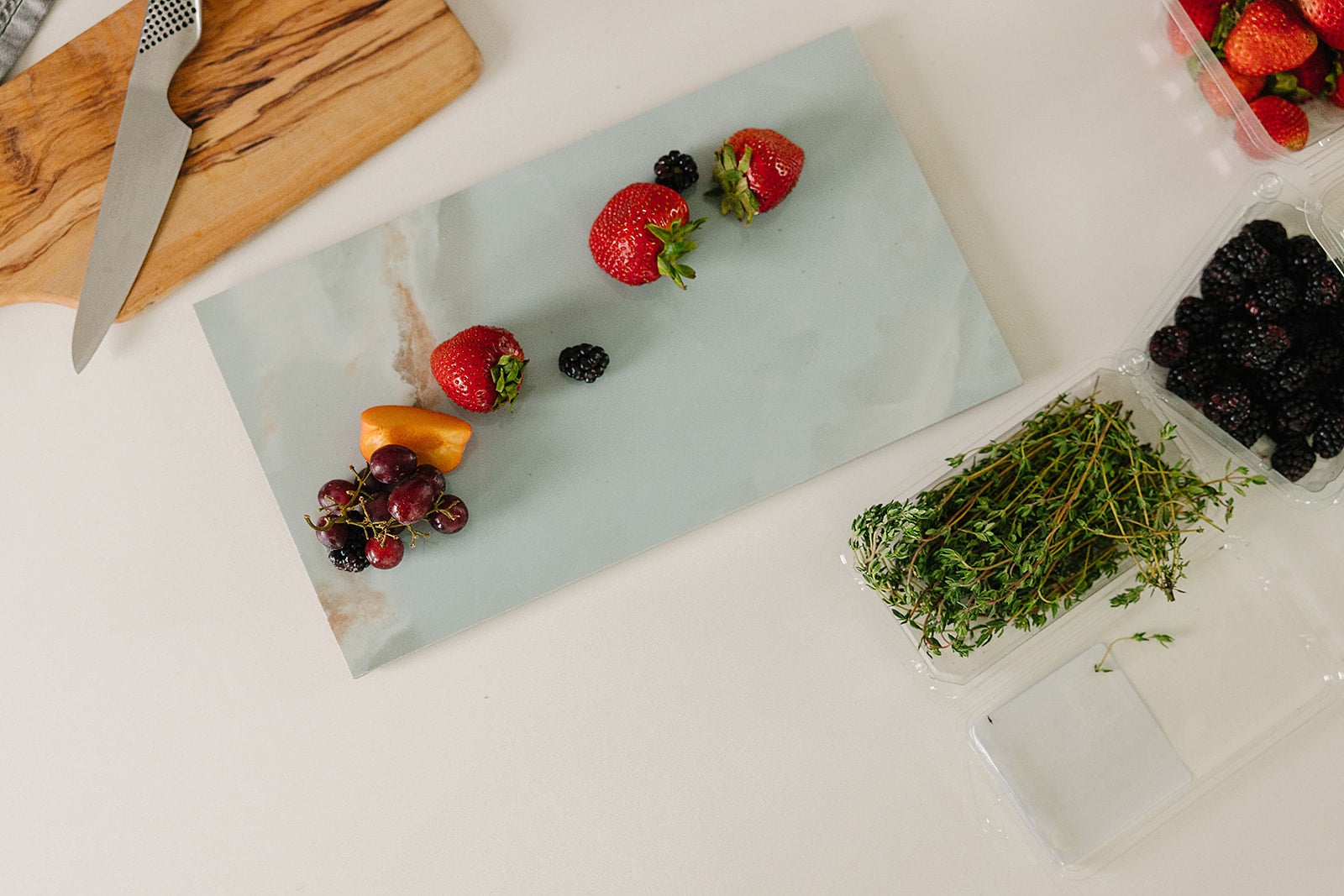 Sage-green Verona porcelain charcuterie board styled with fresh fruit for entertaining