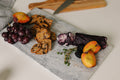 Aleutian Signature Set: handcrafted marble charcuterie board gift set styled with cheese, crackers, and fresh fruit