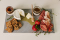 Cortina porcelain charcuterie board fully styled with meats, cheeses, fruit, and crackers for entertaining