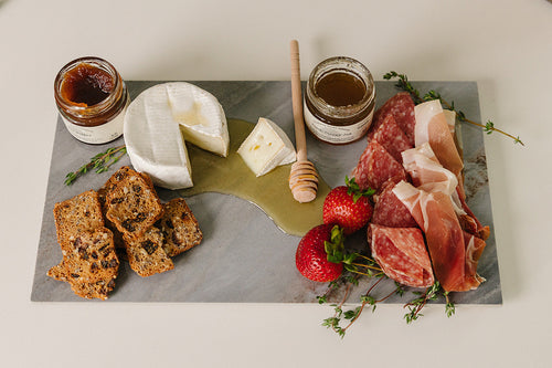 Cortina porcelain charcuterie board fully styled with meats, cheeses, fruit, and crackers for entertaining
